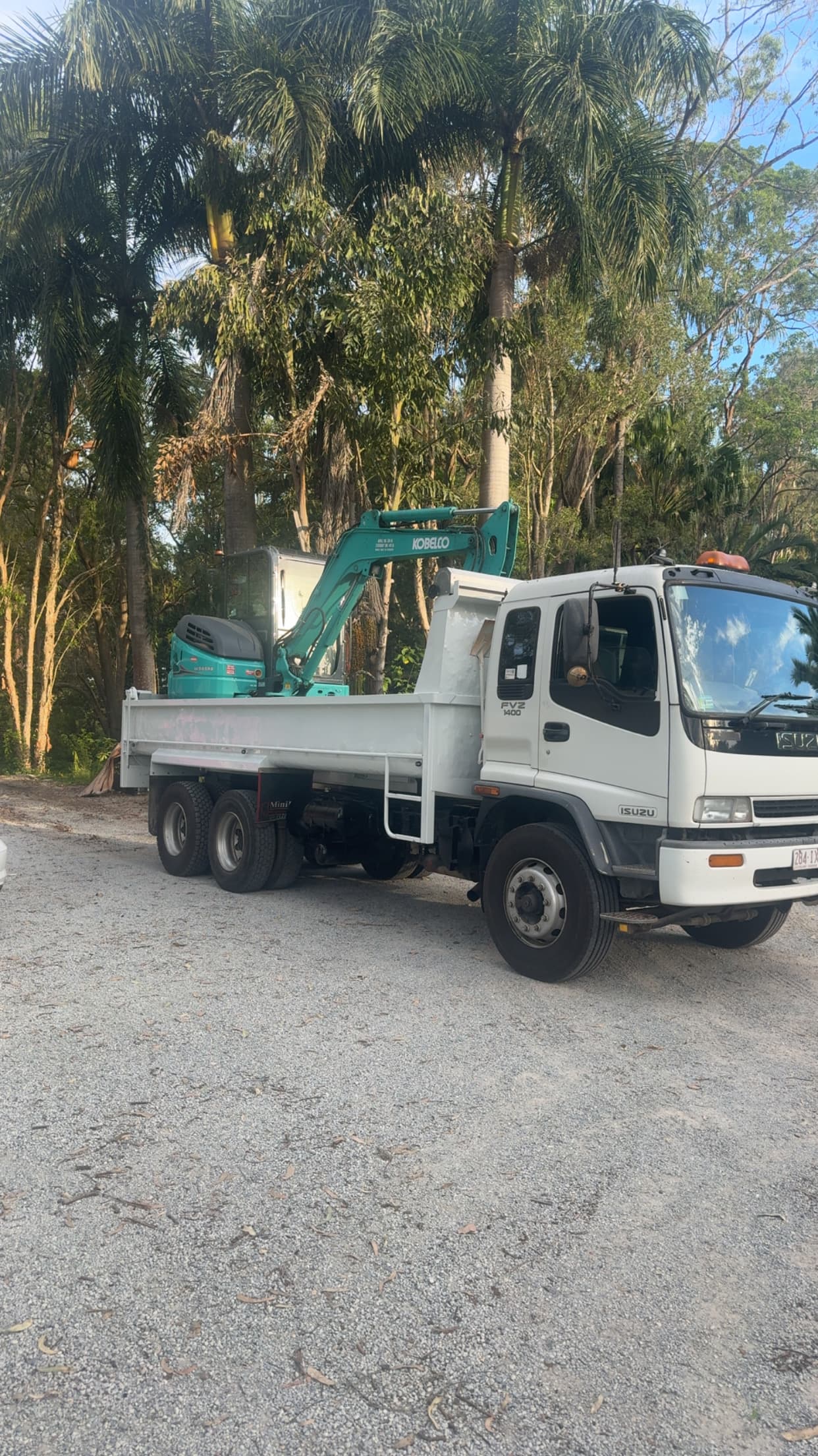 Isuzu tipper truck loaded with Kobelco excavator — material delivery and waste removal across SEQ