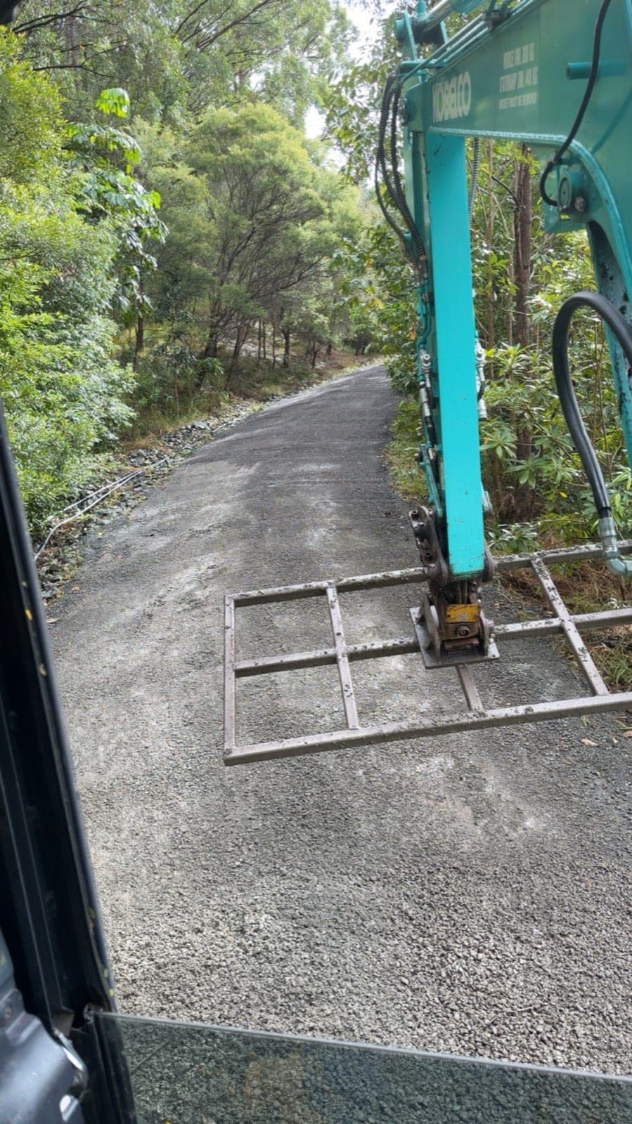 Plate compactor on the excavator compacting road base on a gravel driveway (Southeast Queensland, previous work)