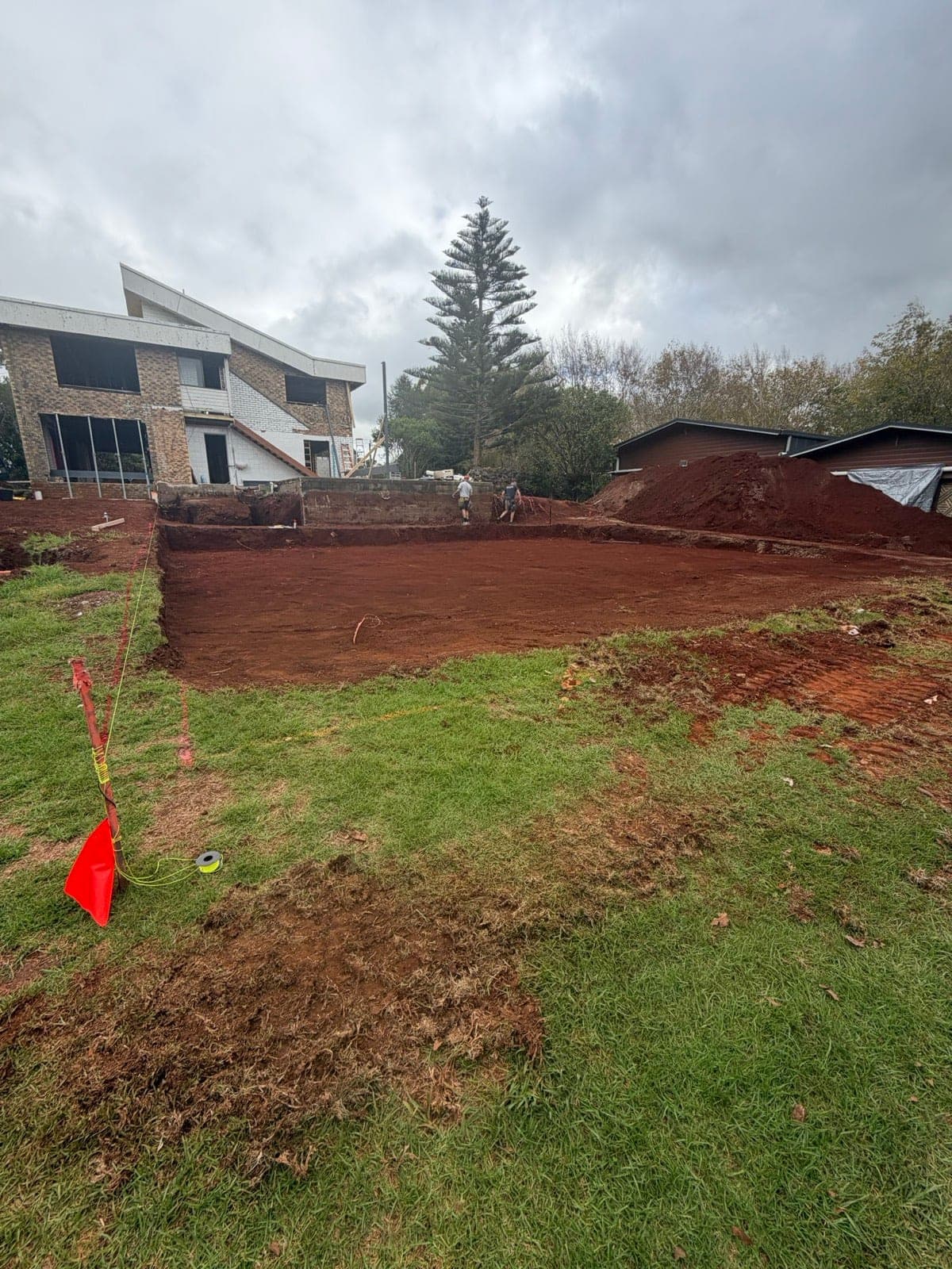 Pad excavation cut to level beside an existing home with spoil stockpiled for removal (Southeast Queensland, previous work)